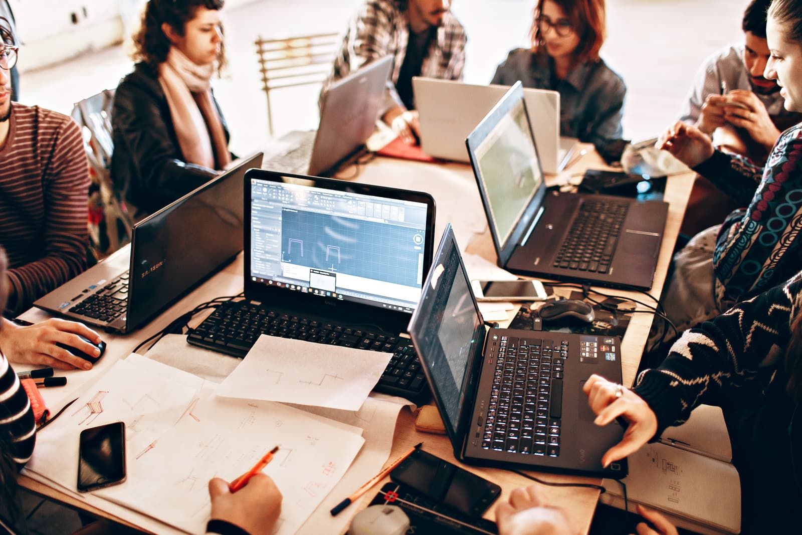 Equipe reunida em mesa de trabalho utilizando notebooks corporativos